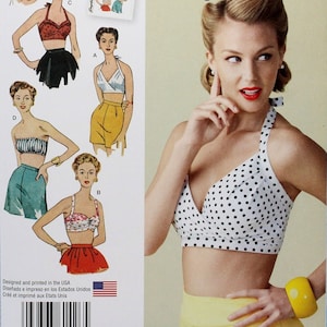 May include: Simplicity sewing pattern number 1426, a vintage 1950s style pattern for a halter top. The pattern includes four different styles of tops, all with a cropped look. The pattern is designed for sizes US 14-22, EU 40-48, and FR 42-50.
