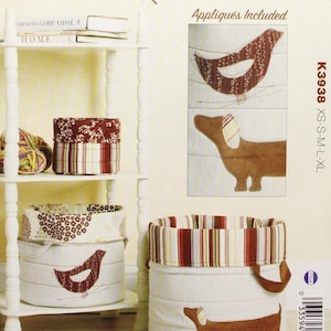 May include: A sewing pattern titled "KWIK SEW K3938 Baskets" by Kerstin Martensson. The pattern includes appliqués of a bird and a dachshund. The baskets are shown in white fabric with red and brown accents. Sizes XS-S-M-L-XL are included.