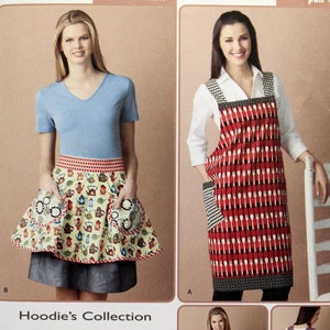 May include: A sewing pattern for a reversible apron with a pull-over style. The pattern includes three different apron designs: one with a red and white spoon print, one with a green and white floral print, and one with a purple and white floral print. The pattern is from Simplicity and is size one size.