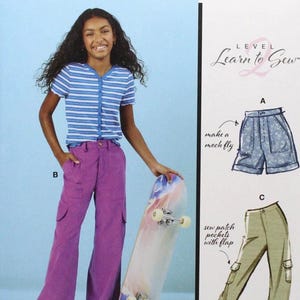 May include: McCall's sewing pattern featuring a young person wearing purple pants and a striped shirt, holding a skateboard. The pattern includes illustrations for shorts and pants with pockets. The text reads "Learn to Sew".