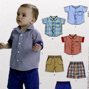 May include: A McCall's sewing pattern for baby and toddler clothing. The pattern includes options for shirts and shorts. The image shows a baby wearing a blue and white checkered shirt and blue shorts. The pattern number is M6016.
