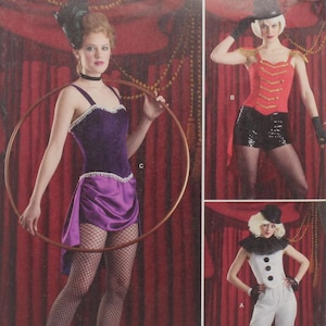May include: Simplicity sewing pattern featuring three circus-themed costumes. The costumes include a purple velvet and satin outfit with a hoop, a red jacket with black shorts, and a white jumpsuit with a black collar and cuffs. The pattern is marked S8972.
