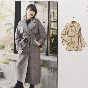 May include: A McCall's sewing pattern packet featuring a woman wearing a long, plaid trench coat. The pattern includes a line drawing of the coat and the text "McCall's" at the top. The packet also includes the size range F5 (16-18-20-22-24).