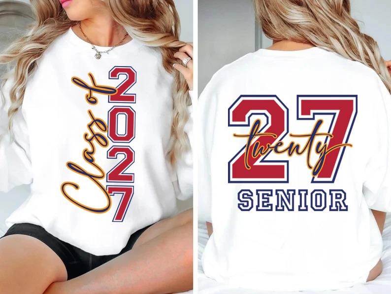 May include: White sweatshirt with "Class of 2027" and "2027" in red and gold lettering on the front. The back of the sweatshirt features "27 Twenty SENIOR" in red, white, and gold lettering. A graduation-themed apparel item.