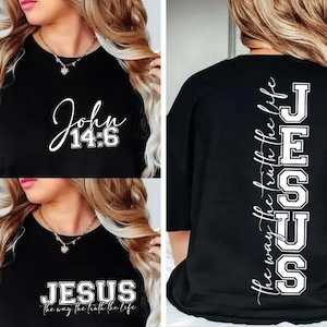 May include: Black t-shirt with white text. The front features "John 14:6" in a script font. The back displays "JESUS" vertically, with "the way the truth the life" written alongside. A second shirt in the image also displays "JESUS".