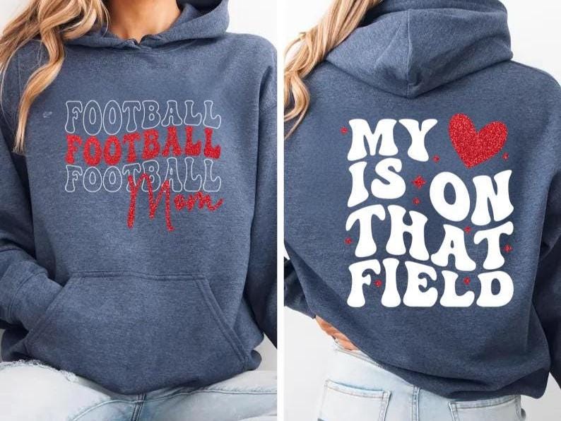 May include: A navy blue hoodie with the words "FOOTBALL FOOTBALL FOOTBALL Mom" in white and red lettering on the front. The back of the hoodie has the phrase "MY HEART IS ON THAT FIELD" with a red heart graphic.