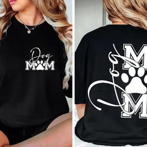 May include: Black t-shirt with the text "Dog Mom" and a paw print design. The back of the shirt features the word "Mom" with a paw print and a cursive design. A casual, comfortable style.