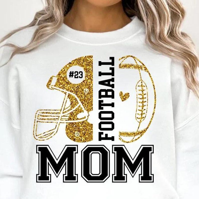 May include: White sweatshirt with a gold glitter football helmet and football design. The word "FOOTBALL" is printed vertically in black, and "MOM" is printed in bold black letters. The helmet has the number "23".