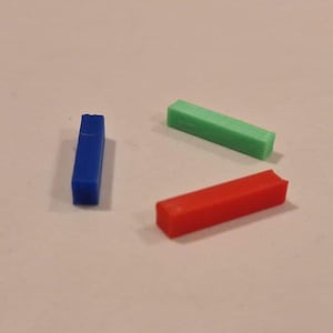 Op de afbeelding: Drie kleine rechthoekige blokken, een blauwe, een rode en een groene.