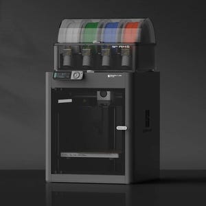 May include: A black 3D printer with a clear filament holder on top. The filament holder has four spools of filament in different colours: red, blue, green, and white. The printer has a digital display and a control panel on the front.
