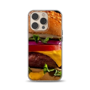May include: A close-up of a cheeseburger with lettuce, tomato, onion, and cheese. The burger is on a clear phone case.