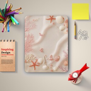 Op de afbeelding: Een roze en wit strandthema ontwerp met koraal, schelpen en zeesterren. Het ontwerp is perfect voor een telefoonhoesje of laptop skin.