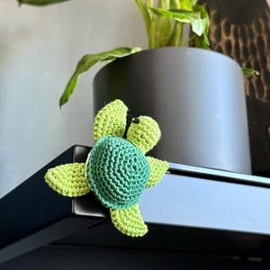 Könnte beinhalten: Eine gehäkelte Schildkrötenfigur in Grün und Limettengrün.