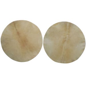 May include: Two round, light tan drumheads with natural variations in color and texture. The drumheads are made of a stretched, animal hide material, and are set against a white background. The drumheads are likely for a percussion instrument.