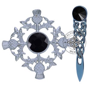 K&ouml;nnte beinhalten: Zwei silberne Broschen mit schwarzen Edelsteinen. Eine Brosche zeigt ein keltisches Knotendesign und die andere ein Kleeblattdesign mit einer Distel in jeder Ecke.