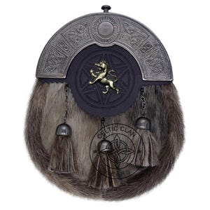 K&ouml;nnte beinhalten: Ein traditioneller schottischer Sporran mit einem Fellk&ouml;rper und einem dekorativen Metall-Cantle. Der Sporran hat eine schwarze Lederklappe mit einem goldfarbenen L&ouml;wenemblem und einem Sterndesign. Drei Quasten h&auml;ngen von unten.