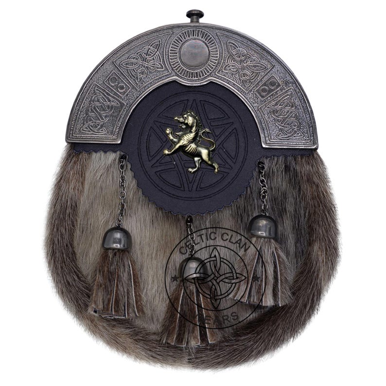 K&ouml;nnte beinhalten: Ein traditioneller schottischer Sporran mit einem Fellk&ouml;rper und einem dekorativen Metall-Cantle. Der Sporran hat eine schwarze Lederklappe mit einem goldfarbenen L&ouml;wenemblem und einem Sterndesign. Drei Quasten h&auml;ngen von unten.