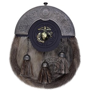K&ouml;nnte beinhalten: Ein traditioneller Kilt-Sporran mit einem Fellk&ouml;rper und einem dekorativen Metall-Cantle. Der Cantle zeigt keltische Knotenmuster und ein zentrales Emblem. Der Sporran hat drei Quasten und Kettendetails.