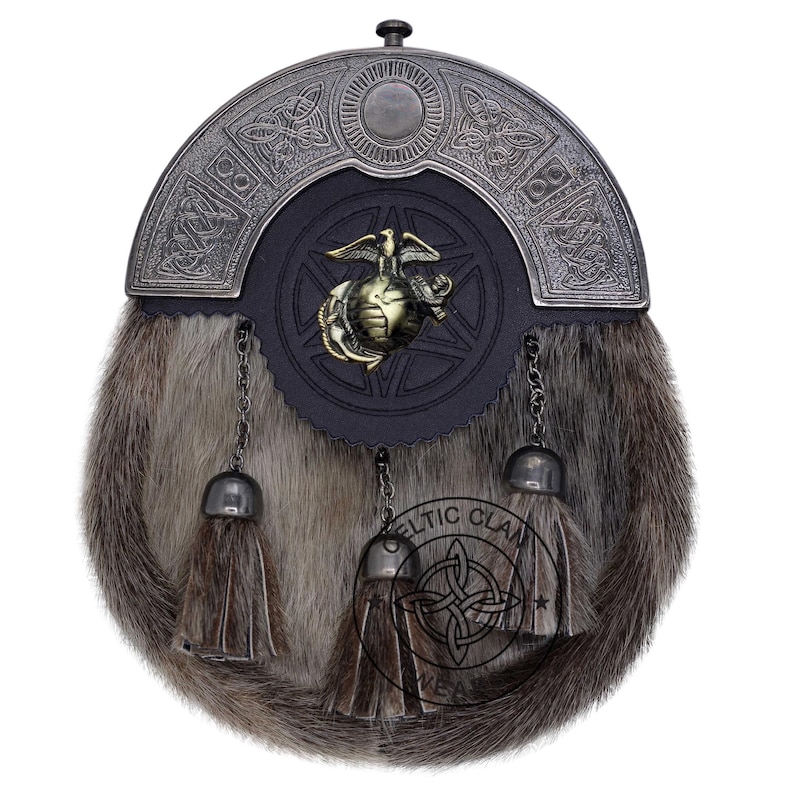 K&ouml;nnte beinhalten: Ein traditioneller Kilt-Sporran mit einem Fellk&ouml;rper und einem dekorativen Metall-Cantle. Der Cantle zeigt keltische Knotenmuster und ein zentrales Emblem. Der Sporran hat drei Quasten und Kettendetails.
