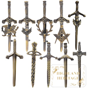 May include: A collection of antique-style letter openers in various designs. The openers are made of a bronze-colored metal and feature intricate details, including a dragon, thistle, and Masonic symbols. The blades are approximately 8 inches long.