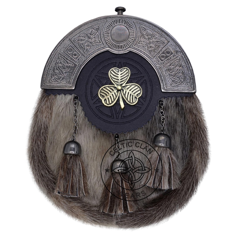 K&ouml;nnte beinhalten: Ein traditioneller schottischer Sporran mit einem Fellk&ouml;rper und einem dekorativen Metall-Cantle. Der Sporran hat eine schwarze Lederfront mit einem goldenen Kleeblatt-Emblem und h&auml;ngenden Quasten. Der Cantle hat keltische Knotenmuster.