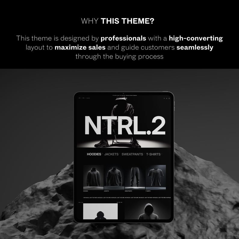 May include: A digital tablet shows a website with the text "NTRL.2" in bold white letters. The website displays clothing items such as hoodies, jackets, sweatpants, and t-shirts. The image is in grayscale, with a dark background and a rocky foreground.