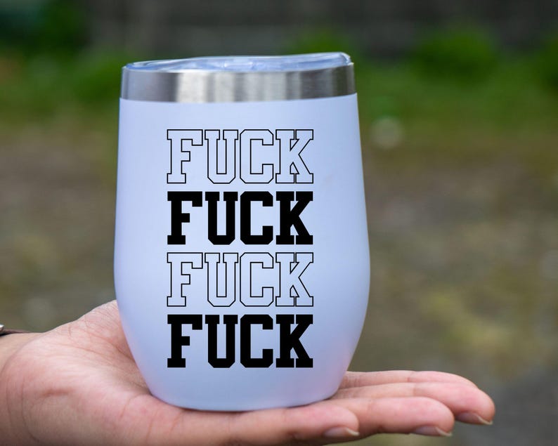 May include: A white insulated tumbler with a silver rim, featuring the word "FUCK" stacked four times in a bold, black, collegiate-style font. The tumbler is held in a hand against a blurred green background.