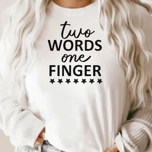 May include: White crew neck sweatshirt with the text "two words one finger" in black script. Below the text are six black star graphics. The sweatshirt is a casual style.