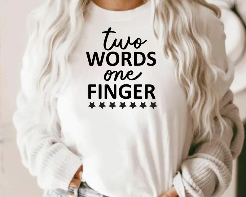May include: White crew neck sweatshirt with the text "two words one finger" in black script. Below the text are six black star graphics. The sweatshirt is a casual style.