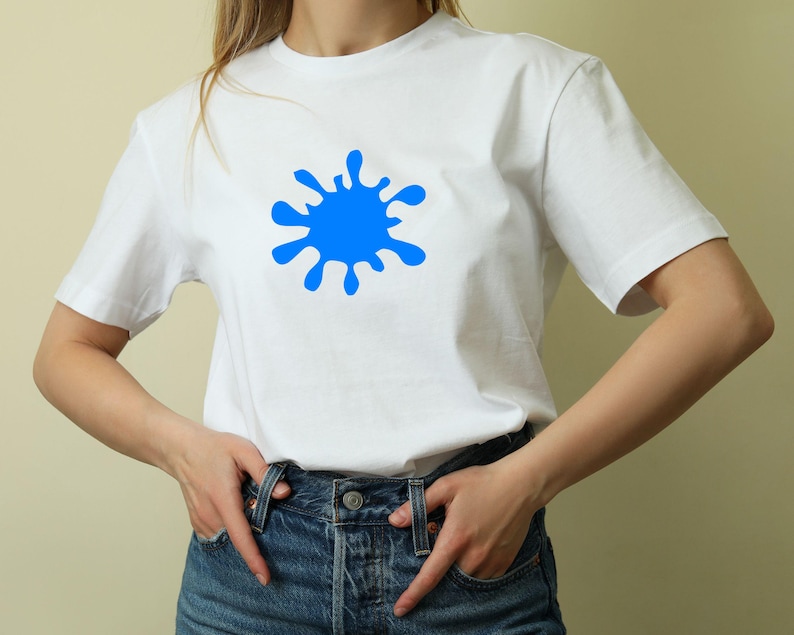 May include: White t-shirt with a large blue paint splatter design. The short-sleeved shirt is made of a soft material and is worn with blue denim jeans. The casual top is suitable for everyday wear.