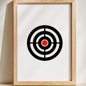 May include: Framed print featuring a target design. The target has concentric black and white rings with a red center. The print is set in a light brown wooden frame, creating a minimalist aesthetic.