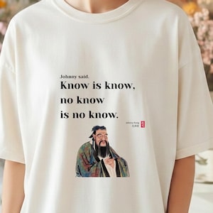 Può includere: T-shirt color crema con la citazione "Know is know, no know is no know" e un'illustrazione di un uomo saggio. La maglietta ha un girocollo e maniche corte. Il testo e l'immagine sono centrati.