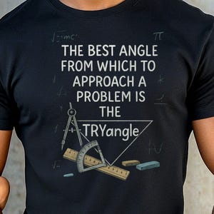 May include: Black t-shirt with the text "THE BEST ANGLE FROM WHICH TO APPROACH A PROBLEM IS THE TRYangle." The design includes a triangle, compass, protractor, and ruler. Mathematical symbols are also present.