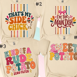 Puede incluir: Cuatro camisetas de color crema con estampados gráficos. La camiseta 1 dice THAT'S MY SIDE CHICK con un pollo. La 2 dice I'M THE MAIN DISH con un lazo. La 3 dice KIND OF A RUDE POTATO ZERO FILTER. La 4 dice SWEET POTATO con un lazo.