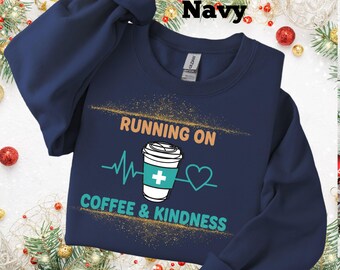 Op de afbeelding: Marineblauwe sweatshirt met de tekst "RUNNING ON COFFEE & KINDNESS". Het ontwerp bevat een koffiekopje, een hartslaglijn en een hartsymbool. De sweatshirt is een crew neck stijl.