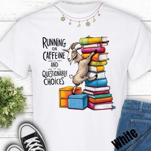 Puede incluir: Camiseta blanca con el texto "Running on Caffeine and Questionable Choices". Una cabra de dibujos animados sube una pila de libros coloridos. La camiseta se combina con vaqueros azules y zapatillas blancas.