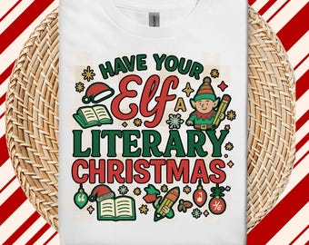 May include: White t-shirt with a colorful graphic that reads "Have Your Elf a Literary Christmas." The design includes an elf, books, pencils, and Christmas ornaments. The shirt is displayed on a woven basket.