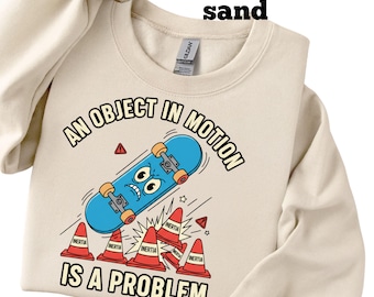 May include: Sand-colored sweatshirt with a graphic of a blue skateboard with a face, red traffic cones, and the text "AN OBJECT IN MOTION IS A PROBLEM."