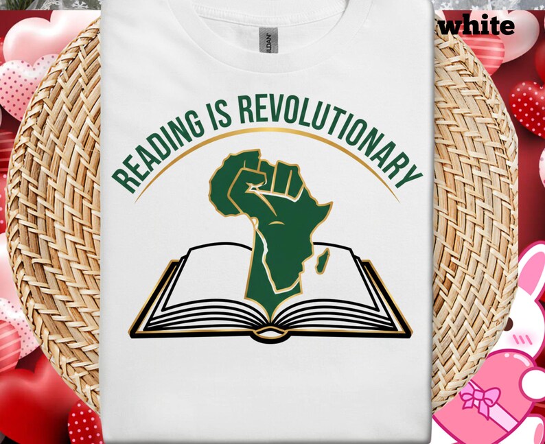 May include: White t-shirt with the text "READING IS REVOLUTIONARY" in green and gold. The design features a green fist rising from an open book, with the outline of the African continent.