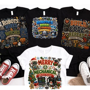 May include: Three black t-shirts and one white t-shirt featuring colourful graphic prints. The designs include text such as Robots Wires & Witches, Robotics Mode Activated, Build Code Repeat, and Merry & Mechanical, alongside various robot and holiday illustrations.
