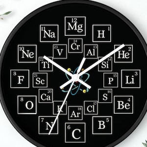 May include: A black wall clock featuring a periodic table design. White numbers and element symbols are arranged around the clock face. White clock hands point to the time. The clock has a black frame.