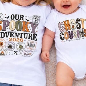 May include: A white t-shirt featuring the text OUR SPOOKY ADVENTURE 2026 with Halloween-themed stamps and a white baby bodysuit with the text GHOST COUSINS Making Memories Since Day One, both decorated with orange, black, and purple patterned lettering.
