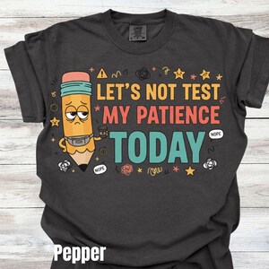 May include: Dark gray t-shirt with the text "LET'S NOT TEST MY PATIENCE TODAY" in various colors. A cartoon pencil with a sad face and a coffee cup is featured on the left side of the graphic. The word "Pepper" is at the bottom.