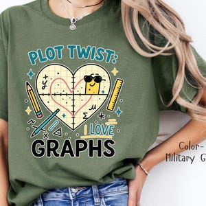 Puede incluir: Camiseta verde militar con un diseño gráfico que presenta un gráfico en forma de corazón, un lápiz, una regla y el texto "PLOT TWIST: I LOVE GRAPHS". El diseño incluye un cuadrado amarillo con gafas de sol.