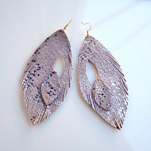 Boucles d’oreille en plume en cuir. Lumière brillante. Double pour la plume. Chaîne à travers.