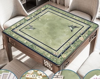 May include: A wooden game table with a green surface featuring hummingbird and floral designs. The table is surrounded by chairs and is shown with playing cards, dominoes, and mahjong tiles, highlighting its versatility. The text "Wide Range of Uses" is at the top.