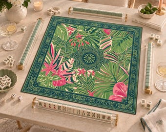 May include: A square mahjong mat featuring a vibrant tropical leaf and floral pattern in shades of green and pink, surrounded by a dark green border. The set includes four clear acrylic tile racks, a collection of mahjong tiles, and two white dice.