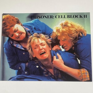 May include: A promotional image for "Prisoner: Cell Block H" featuring three women in blue denim shirts. One woman is crying, while the other two appear to be comforting or restraining her. The image has a vintage aesthetic.