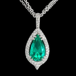 May include: A silver necklace with a pear-shaped pendant. The pendant features a large, vibrant green gemstone surrounded by a halo of small, sparkling white stones. The chain is a delicate double strand.