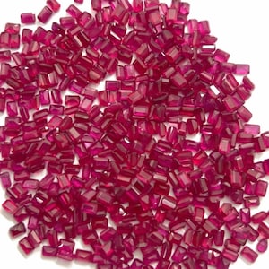 May include: A pile of small, red, rectangular gemstones. The gemstones are faceted and have a shiny, polished finish.